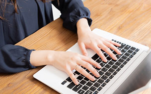 ノートパソコンのキーボードを打つ女性